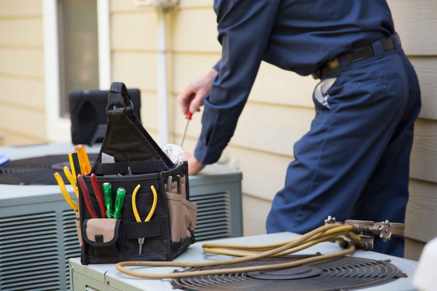 Male HVAC technician servicing an outdoor unit.