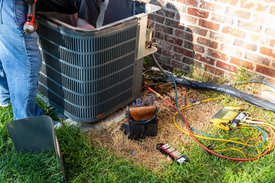 Air conditioner maintenance being performed by a technician on an outdoor unit