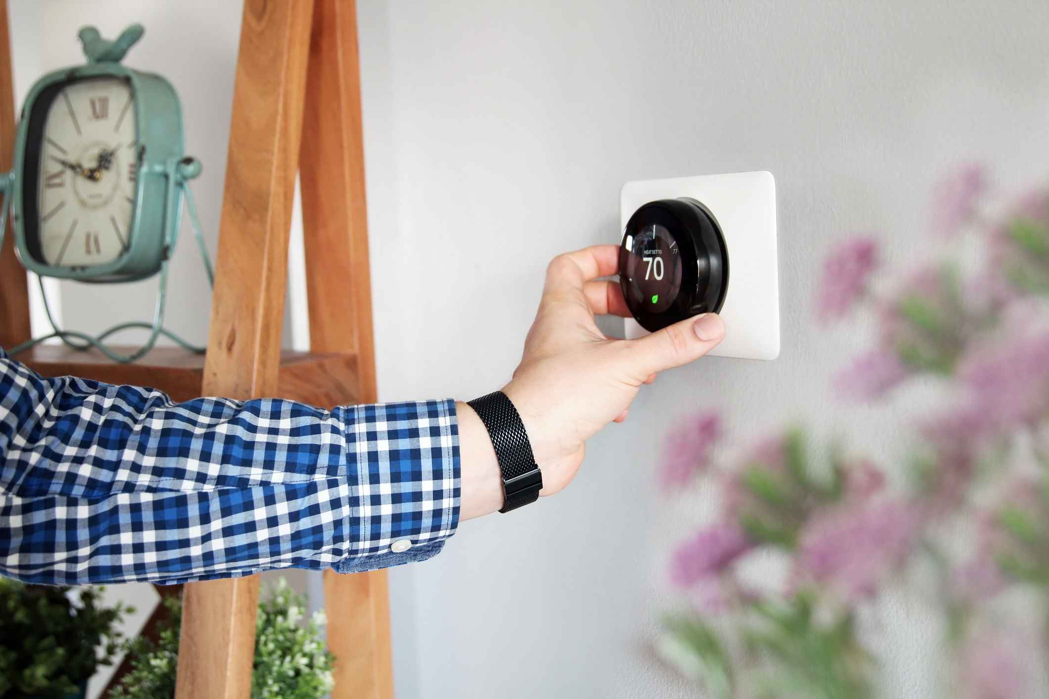 Homeowner adjusting smart thermostat on the wall